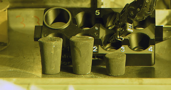 Three cylindrical HALEU fuel cartridges sit in front of the lab equipment